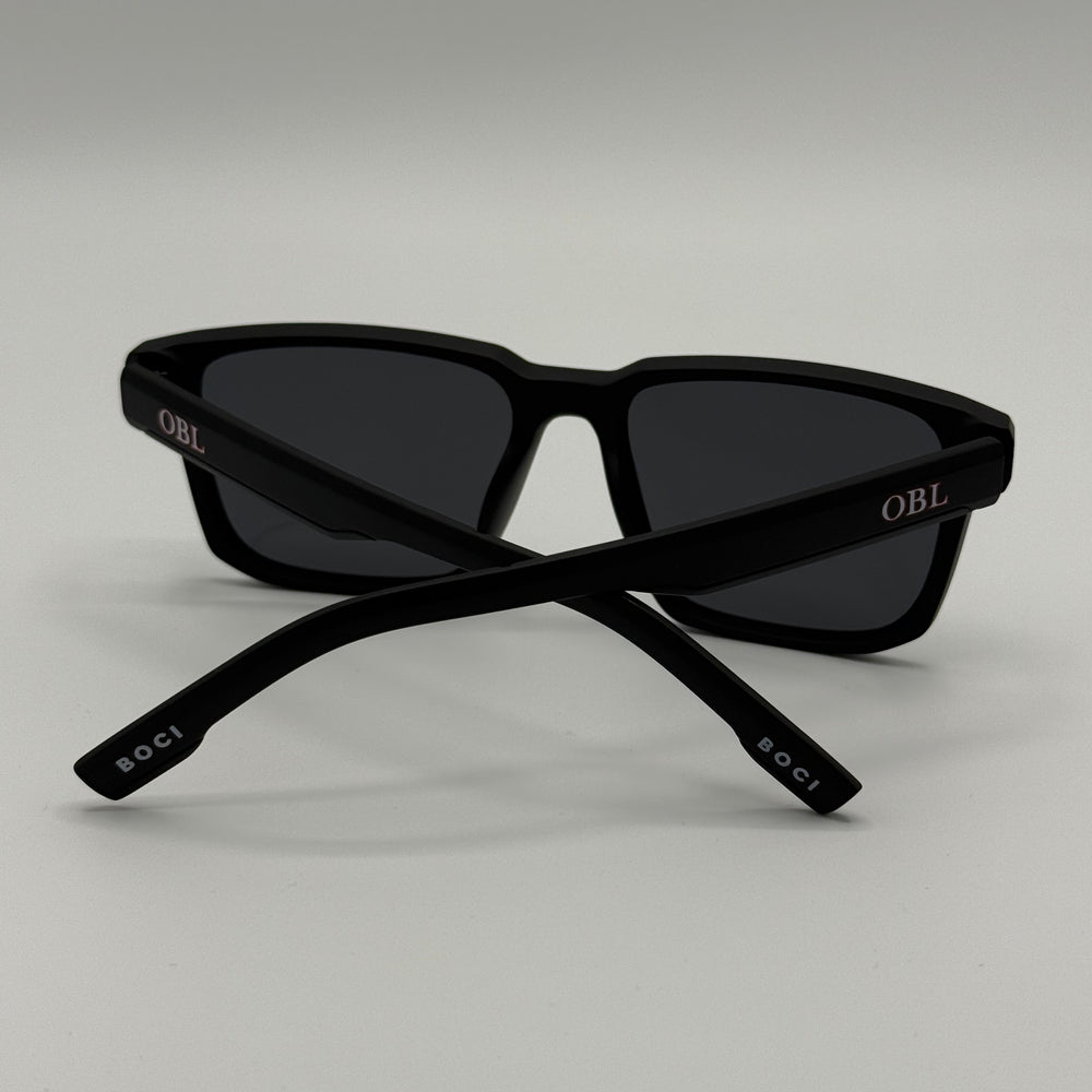 Black sunglasses with 'OBL' branding on a light gray background